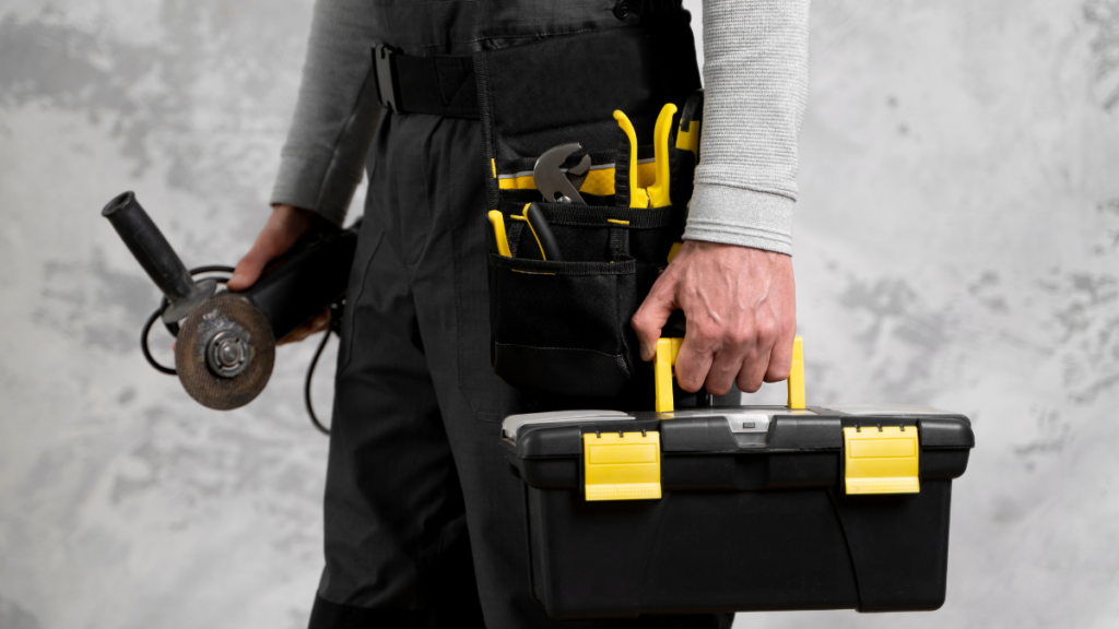 Profissional segurando caixa de ferramentas e esmerilhadeira com cinto organizador em ambiente de trabalho técnico