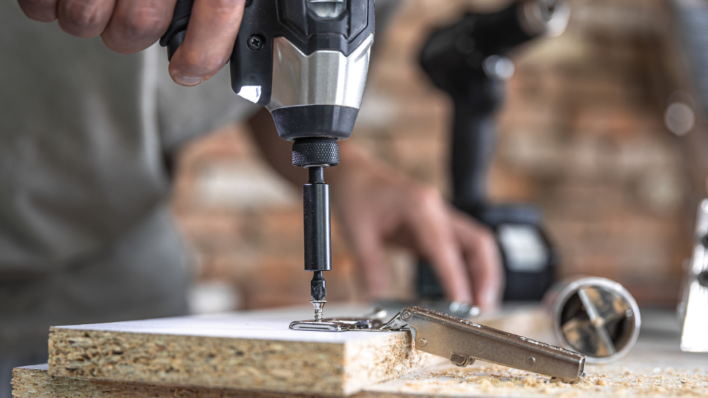 Mestre da Ferramenta utilizando parafusadeira de impacto para fixação de parafuso em painel de madeira MDF em bancada de trabalho