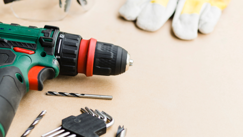 Furadeira elétrica verde e vermelha com brocas e chaves Allen sobre bancada, pronta para uso em serviços de perfuração e montagem. termos de uso